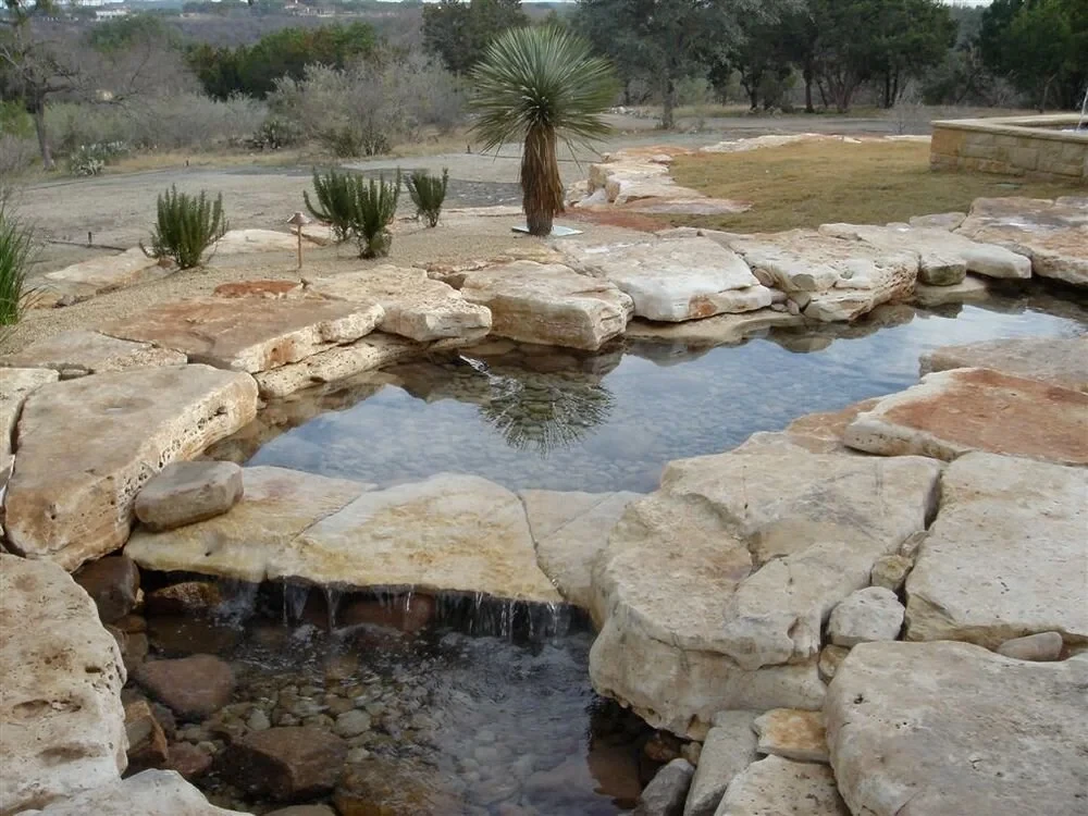 Natural stone spa and waterfall set in limestone slabs above the Hill Country with a yucca