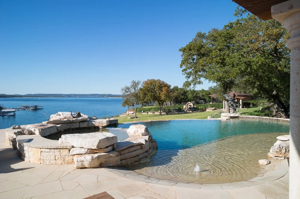 Negative-edge pool blending into Lake Travis, stone spa and flagstone coping along the waterline