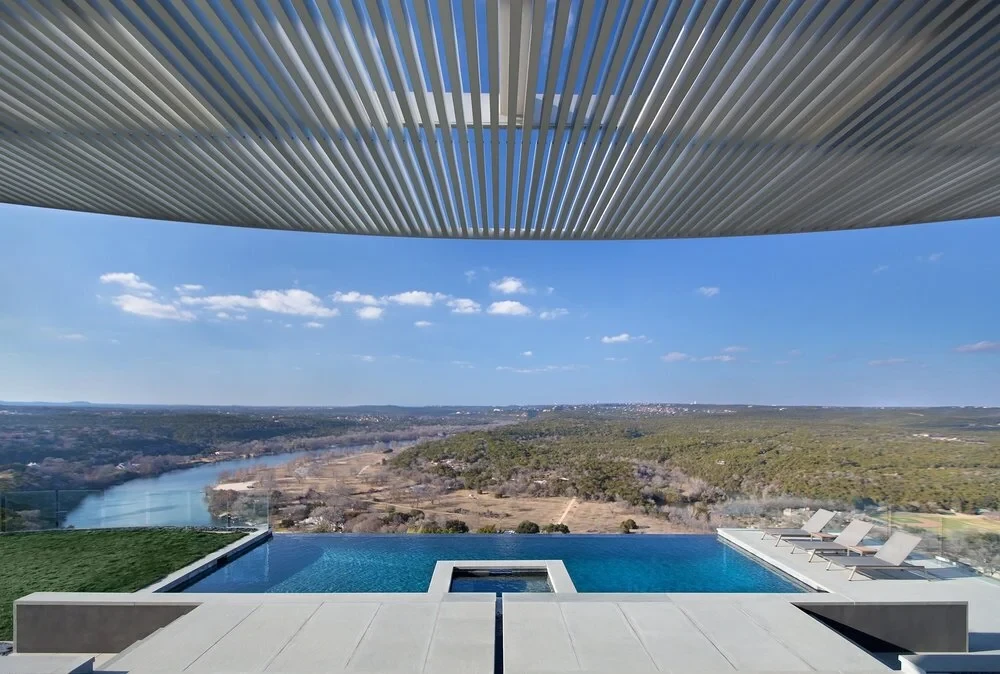 Infinity pool with a raised spa and vanishing edge over the Colorado River and Hill Country, under a slatted canopy