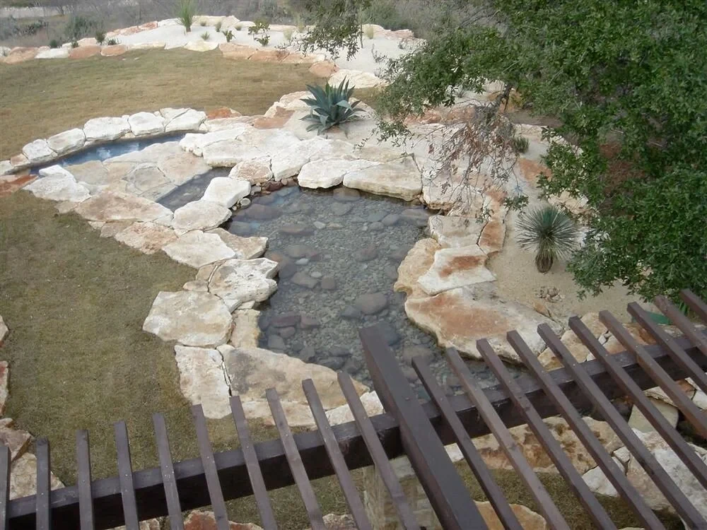 Overhead view of a freeform stone pond and waterfall edged in limestone slabs on a hillside