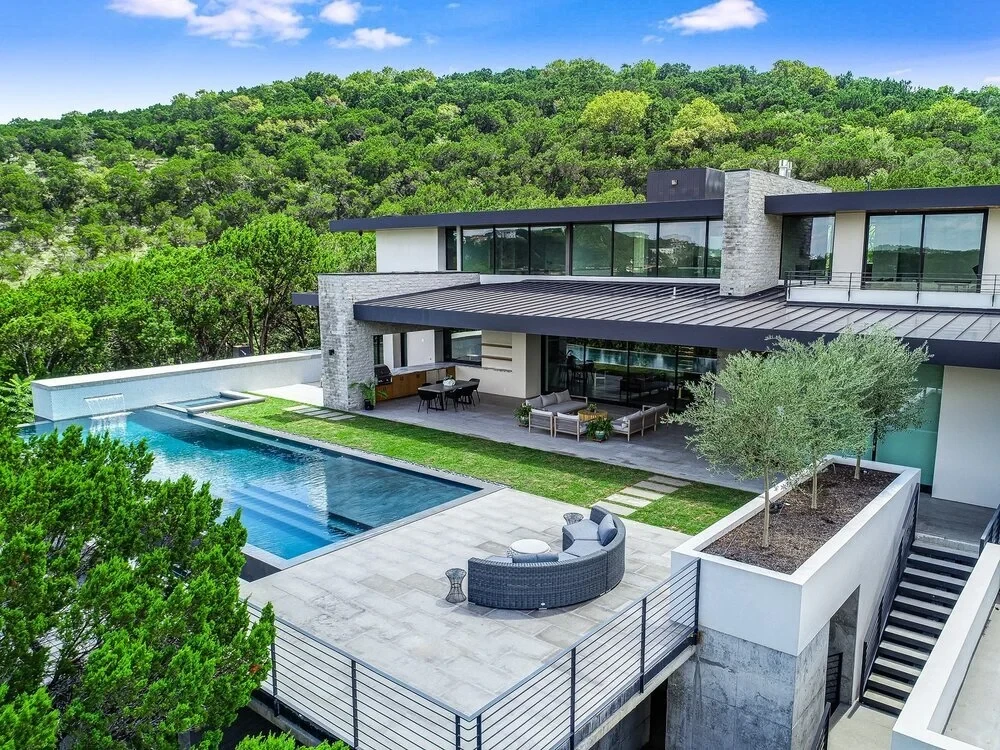 Modern home with an infinity-edge pool cantilevered over wooded Hill Country slopes