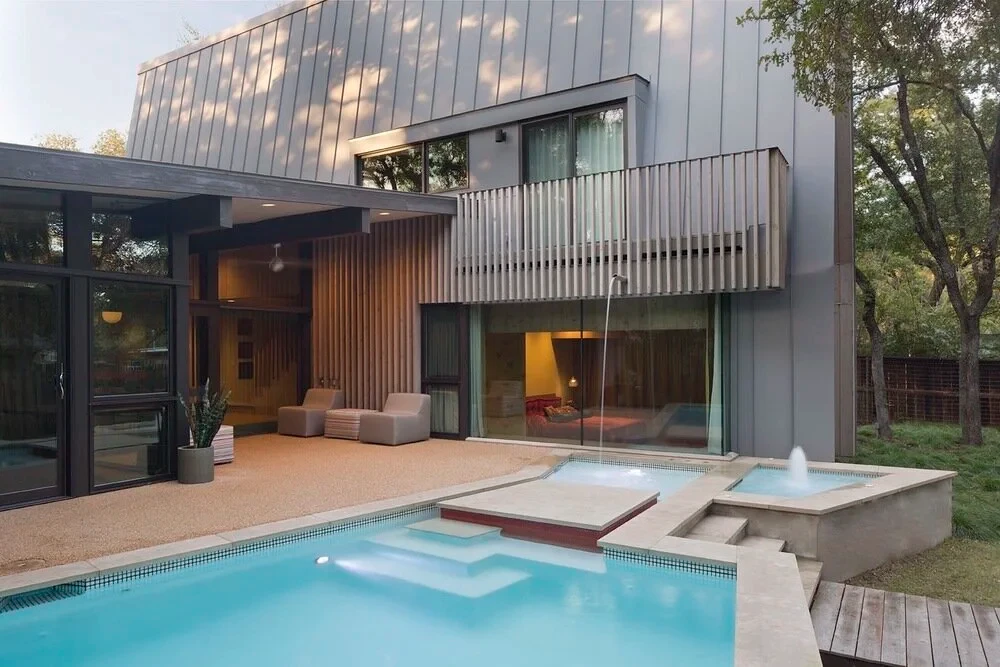 Metal-clad modern home with a slat balcony above a turquoise geometric pool, spa and bubbler