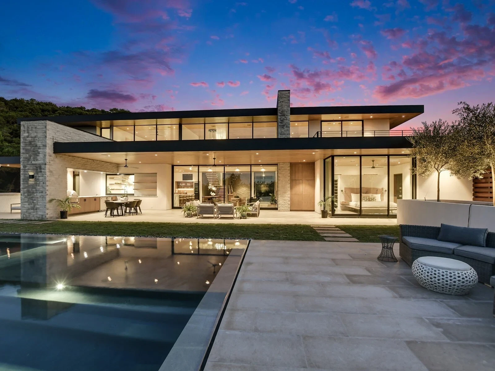 Infinity pool and raised spa overlooking Hill Country hills under a pink and purple sunset